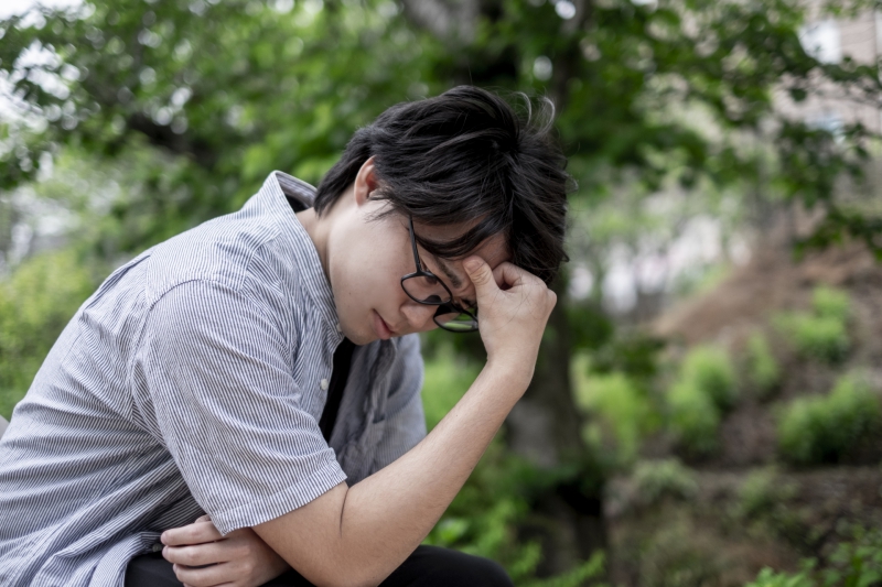 頭を抱えて悩む青年