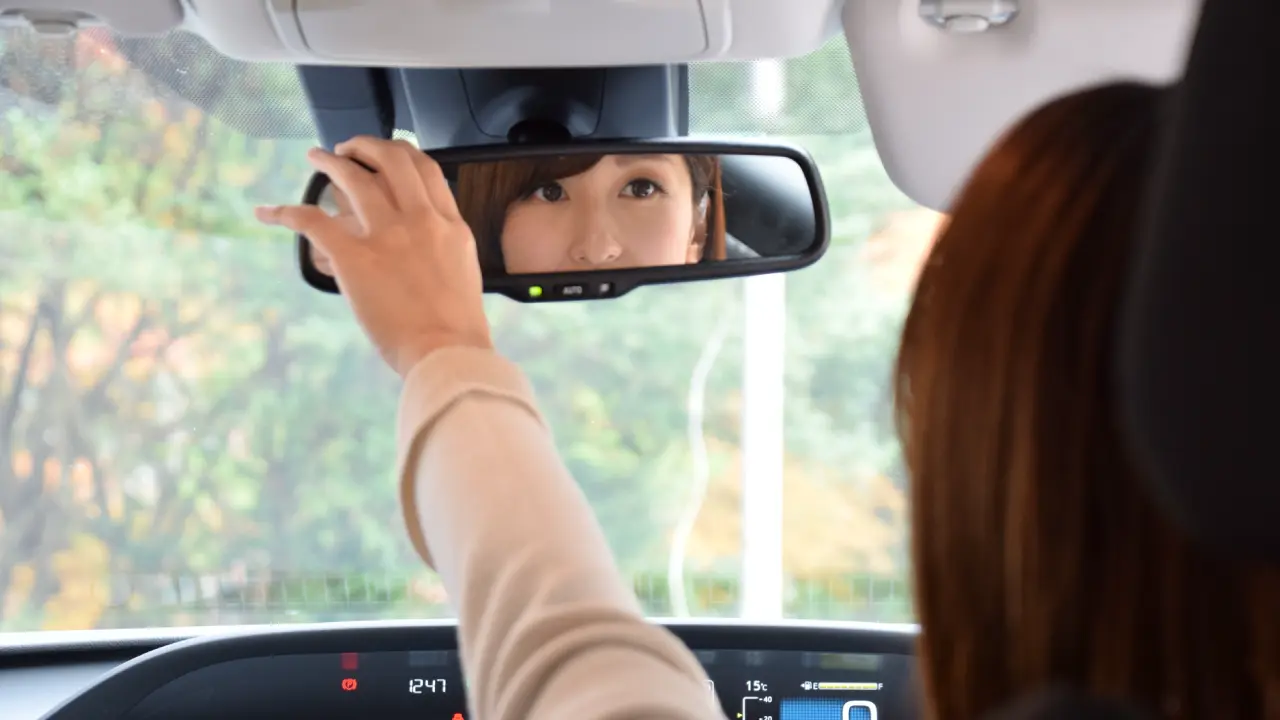 車のバックミラーを直す妻